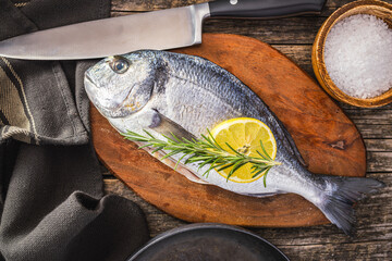 Fresh sea bream fish on cutting board on wooden table. Top view. - 791404576