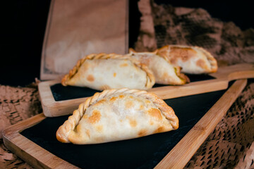 Delicious Argentinian empanadas presented on wooden boards, cardboard background, brown colors
