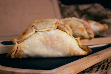 Closeup shot Delicious Argentine empanadas presented on wooden boards, cardboard background