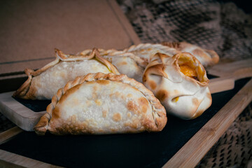 Lots of Argetinas empanadas with different fillings, background decorated with cardboard