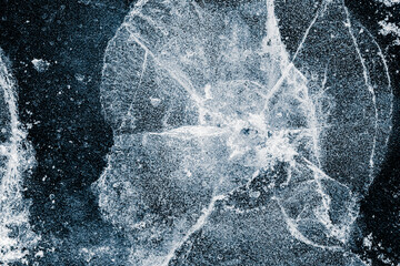 Cracked ice texture background. The textured cold frosty surface of the ice on a black background.