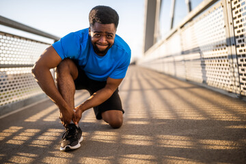 Young african-american man is injured while jogging. He twisted his ankle.