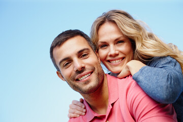 Naklejka premium Couple, portrait and outdoor piggyback by blue sky, together and care for bonding in embrace. People, support and hug on holiday or vacation in nature, low angle and commitment on mockup space