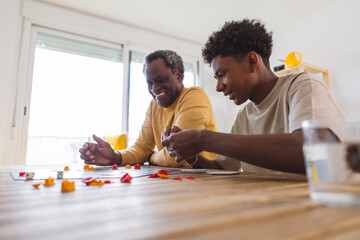 Happy grandfather and grandson playing board game at table