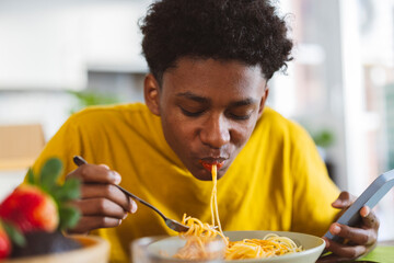 Teenage boy eating noodles at home