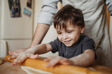 Smiling son helping father in kitchen at home