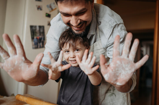 Happy father and son showing palm of hands in kitchen at home