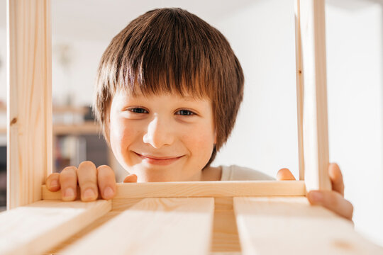 Smiling boy with wooden rack at home