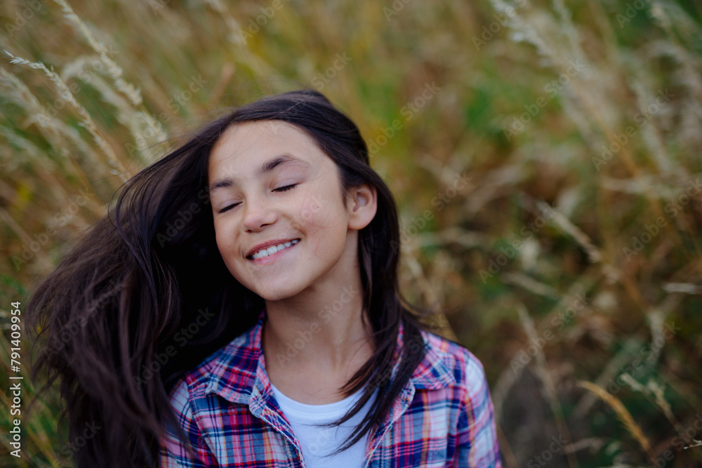 Wall mural Portrait of beautiful young girl standing in nature, in the middle of tall grass, headshot. Copy space.