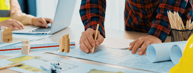 A cropped portrait of professional architect working with blueprint during safety engineer using...