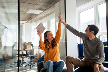 Successful business people giving high-five to each other in office
