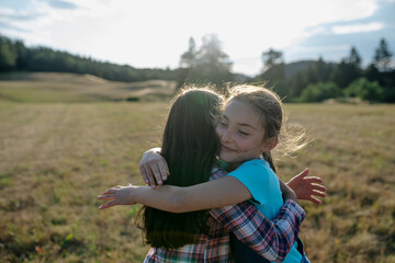 Young girl best friends spending time in nature, during sunset. Girls on walk, embracing.