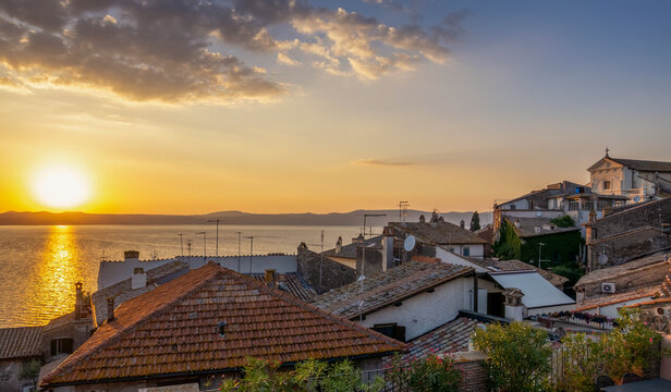 Italy, Lazio, Anguillara Sabazia, Rooftops of houses overlooking lake Bracciano at sunset