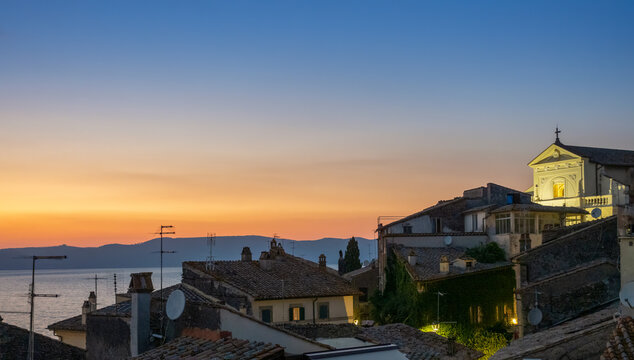 Italy, Lazio, Anguillara Sabazia, Rooftops of houses overlooking lake Bracciano at dusk