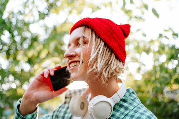 Happy young woman wearing red knit hat and talking on smart phone