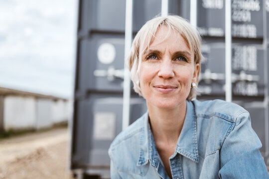 Confident Mid-Adult Blonde Woman in Urban Setting, Looking Up with Positivity