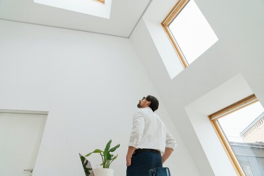Businessman looking at skylight in minimalist office