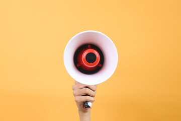 Hand Holds Megaphone Isolated on Yellow Background