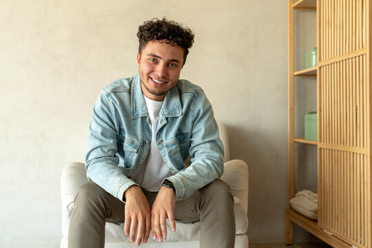 Happy young man sitting on armchair at home