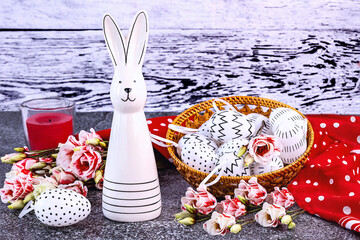 Easter composition with an Easter bunny, white eggs with black polka dots in a basket, a red polka...