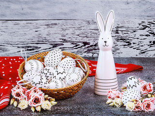 Easter composition with an Easter bunny, white eggs with black polka dots, a red polka dot shawl, a...