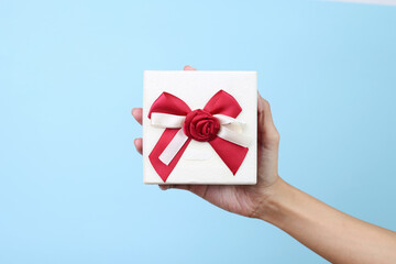 Hand Holds Gift Box Isolated on Blue Background
