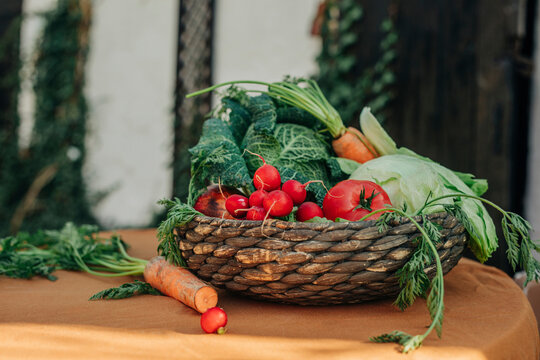 Various fresh organic vegetables in vintage wicker basket on table