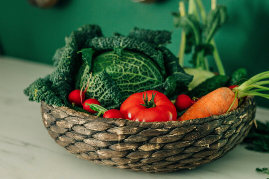 Various fresh vegetables in wicker basket on table in kitchen