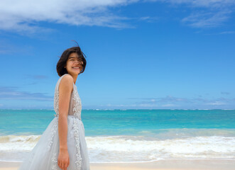 Fototapeta na wymiar Teen girl in white dress walking barefoot on hawaiian beach