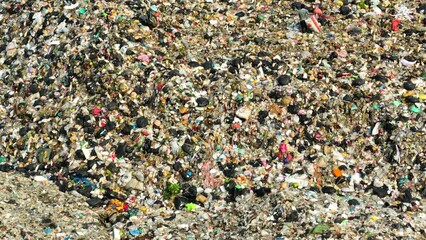 A landfill reveals a dense amalgam of debris, showcasing diverse colors and shapes of waste, spotlighting the environmental impact of consumerism. Landfill background. Aerial view.
