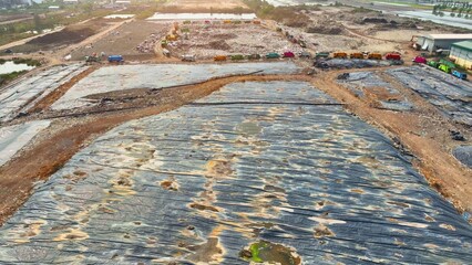 A sprawling landfill concealed under expansive black plastic sheets, a testament from above to...