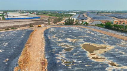 From above, a landfill site is cloaked in darkness with layers of black plastic, a somber shroud concealing our waste. Landfill background. Aerial view.
