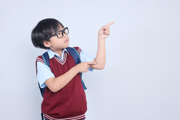 Little Asian student boy pointing aside showing copy space for advertisement.