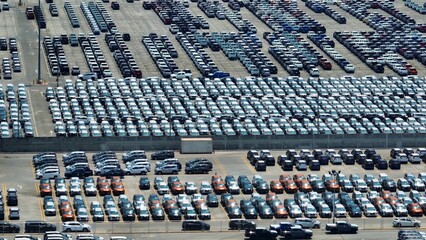A bird's-eye perspective captures a vast parking lot, meticulously organized rows of vehicles...