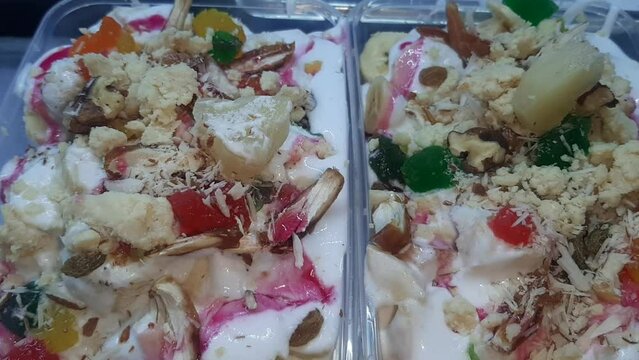 Creami Fruit salad with dry fruits. Fruit Chaat. Mixed cream fruit chaat masala with banana, apple pineapple, dates, pomegranate seeds served in dish top view of pakistani food. Beautiful 4K Footage.