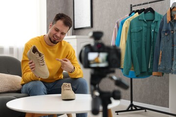 Smiling fashion blogger showing shoes while recording video at home - obrazy, fototapety, plakaty