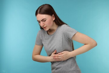 Woman having heart attack on light blue background