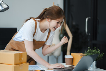Happy young Asian woman entrepreneur, Smile for sales success after checking order from online...