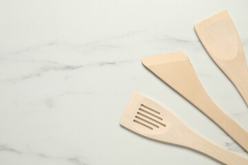 Different wooden spatulas on white marble table, flat lay. Space for text - obrazy, fototapety, plakaty