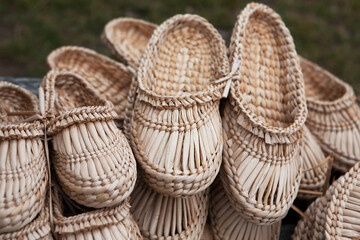 Straw-woven bast shoes lie on the counter. Eco-friendly handmade products. Ukrainian traditional...
