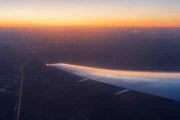 Sunset view from a flying airplane. Beautiful evening aerial landscape. View of an airplane wing. Travel and aviation tourism. Flight on a passenger airliner. - 791428145