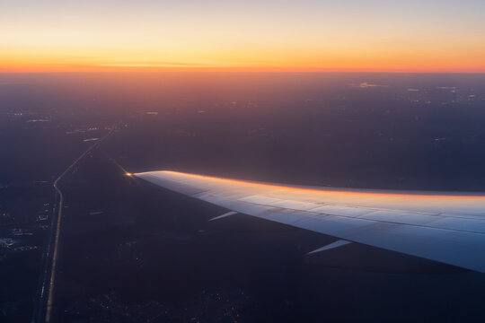 Sunset view from a flying airplane. Beautiful evening aerial landscape. View of an airplane wing. Travel and aviation tourism. Flight on a passenger airliner.