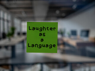 Post note on glass with 'Laughter as a Language'.