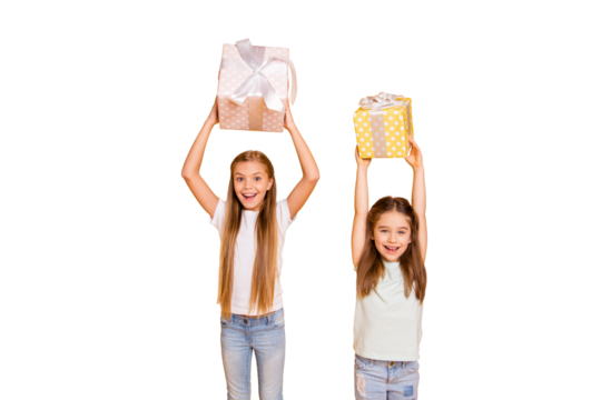 Portrait of two nice cute sweet attractive cheerful funny playful childish girls holding in hands rising over heads large boxes isolated over bright vivid shine yellow background