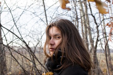 Young woman in sparse forest with worried expression, looking at camera - 791434321
