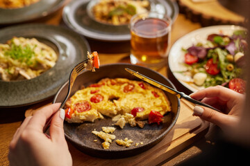 man eating shakshuka or amlet close-up in a stylish cafe and company of friends