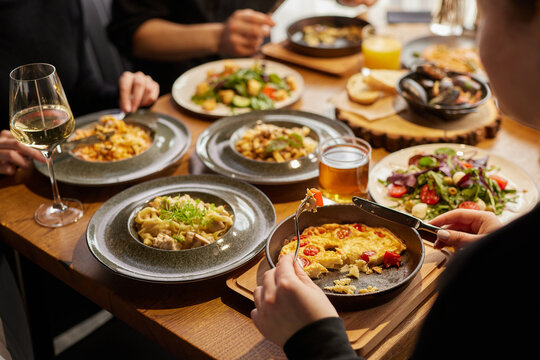 man eating shakshuka or amlet close-up in a stylish cafe and company of friends