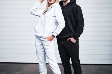 The couple wears blank streetwear hoodies. Man and woman sweatshirt design logo mock-up.