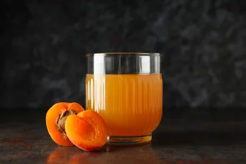Schilderijen op glas A glass of fresh apricot juice on a dark background © Atlas