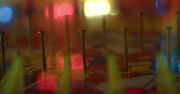 Plinko ball drops and bounces off of nail pins in board at carnival